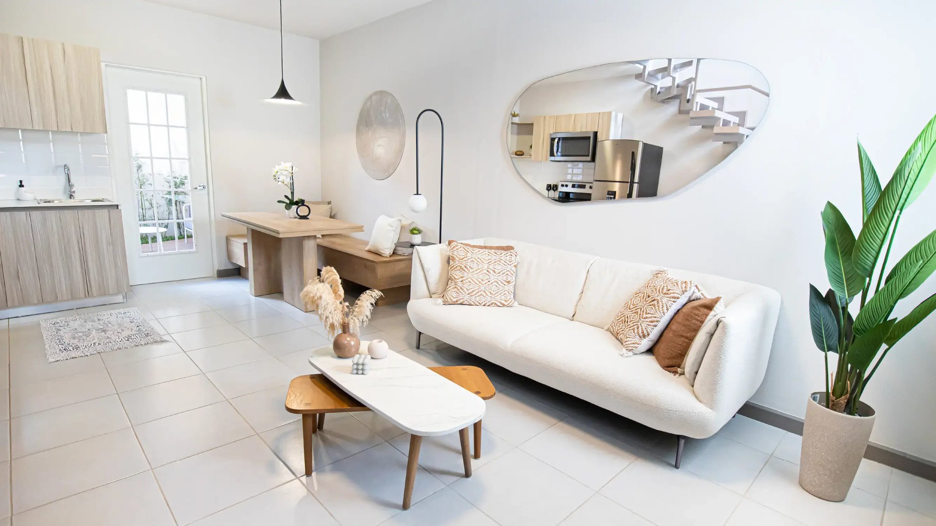 Vista de sala y comedor integrados en casa modelo de Condominio Nova, Desamparados. Muestra sofá, mesa de centro y mobiliario moderno.