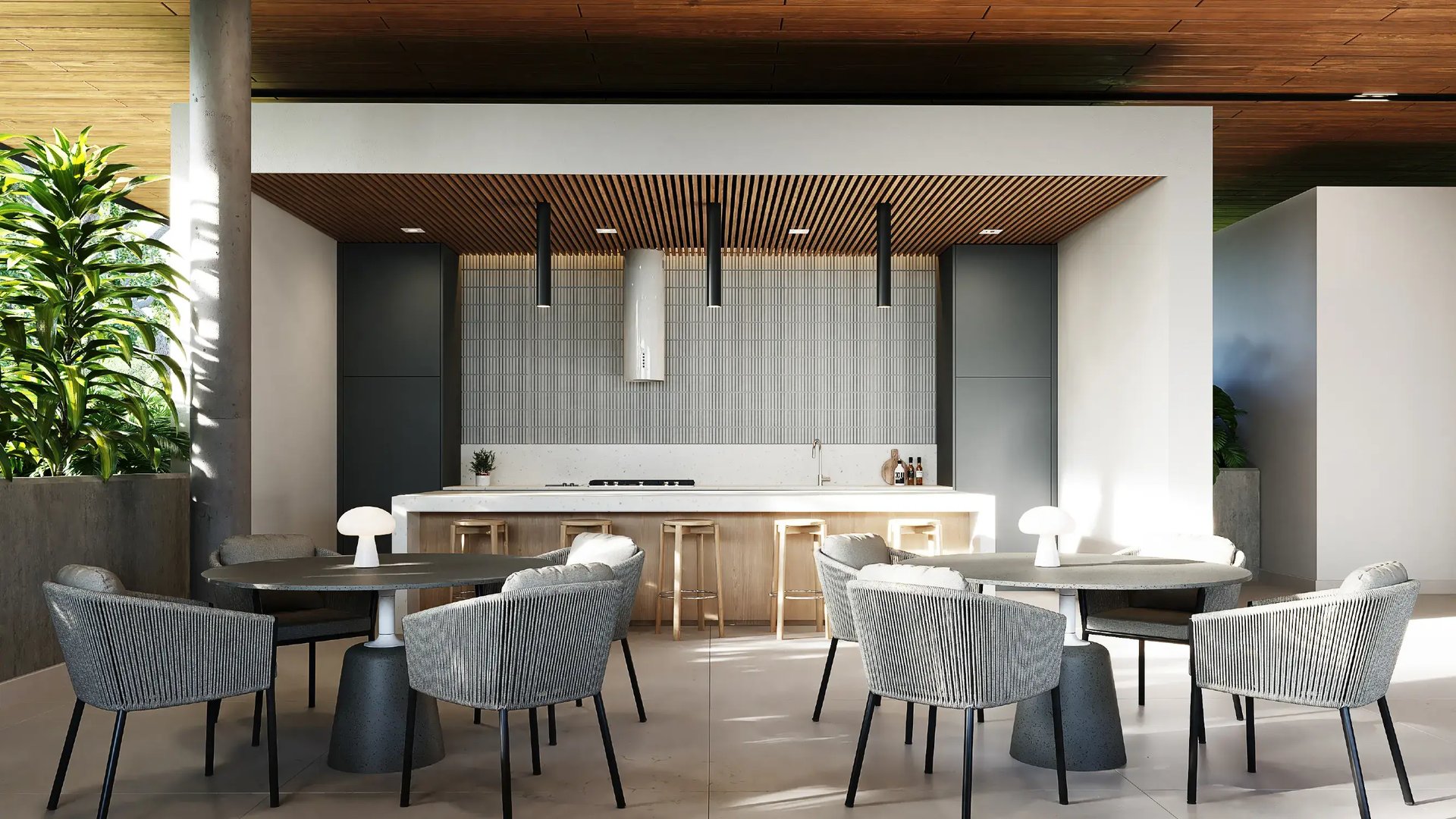 Render interior de casa club con área de comedor y cocina integrada. Presenta mesas circulares modernas con sillas tejidas en gris, barra social con sobres de cuarzo y acabados en madera, bajo un cielorraso decorativo con listones.
