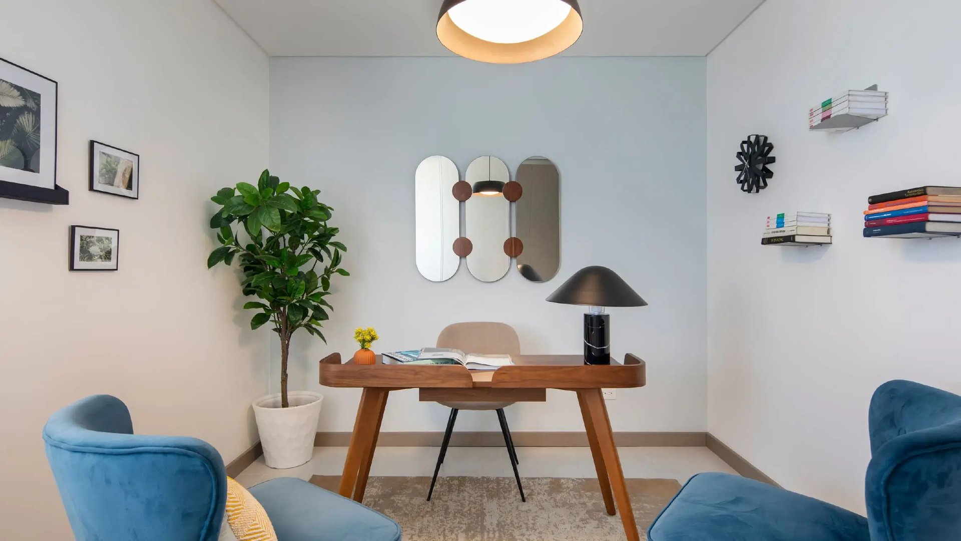 Vista interior del comedor de la casa modelo de Palermo Homes, Heredia. Muestra una mesa rectangular de madera maciza con sillas tapizadas en azul rey y una lámpara colgante moderna.