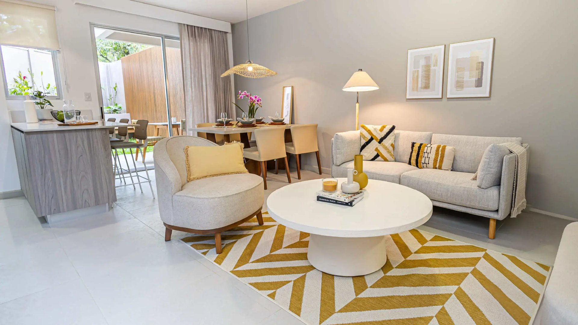 Vista de la sala de estar y comedor de concepto abierto en la casa modelo de Palermo Homes, San Pablo, Heredia. Muestra sillón y sofá contemporáneos, alfombra con diseño geométrico y puertas de vidrio corredizas.