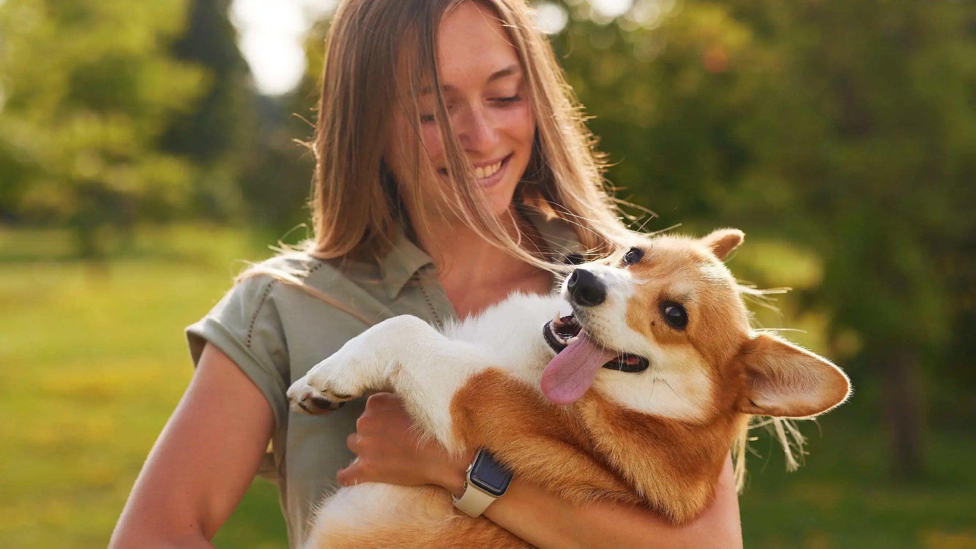 Mujer sonríe abrazando a su perro Corgi en el Pet Park de Palermo Homes, Heredia.