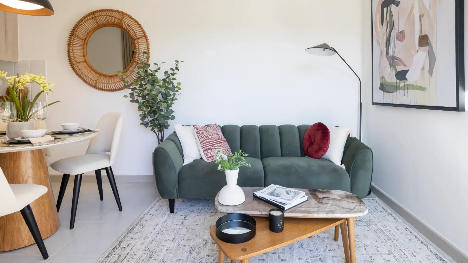 Sala moderna decorada en Condominio Naz, Alajuela. Incluye sofá verde de terciopelo, mesa de centro de mármol, alfombra geométrica y arte contemporáneo en la pared.