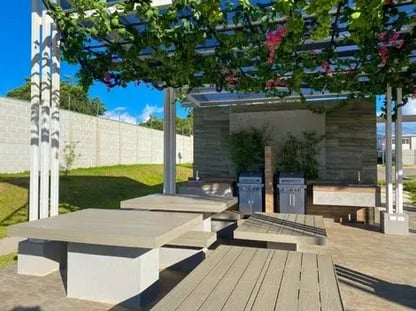 Área de parrillas con pérgola cubierta de plantas mesas de concreto y espacio exterior común