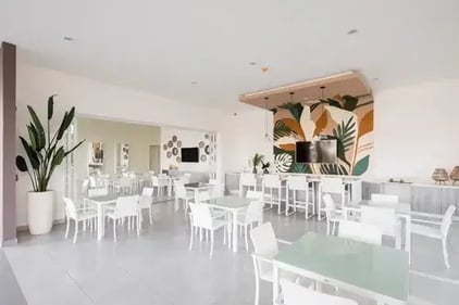 Comedor moderno con mesas y sillas blancas decoración de pared y área amplia interior