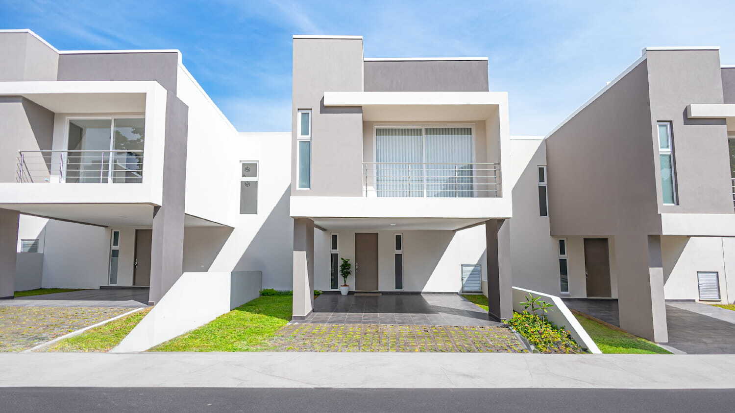 Fachadas de casas modernas de dos pisos en Condominio Nasara, con balcones, cocheras techadas y diseño arquitectónico contemporáneo en tonos blanco y gris.