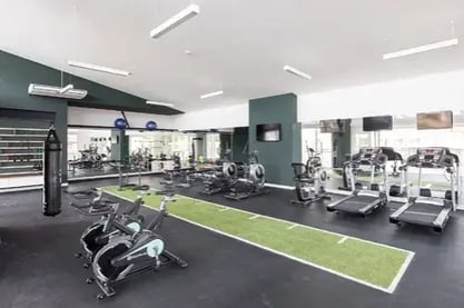 Gimnasio equipado con bicicletas estáticas caminadoras pesas y área de entrenamiento interior
