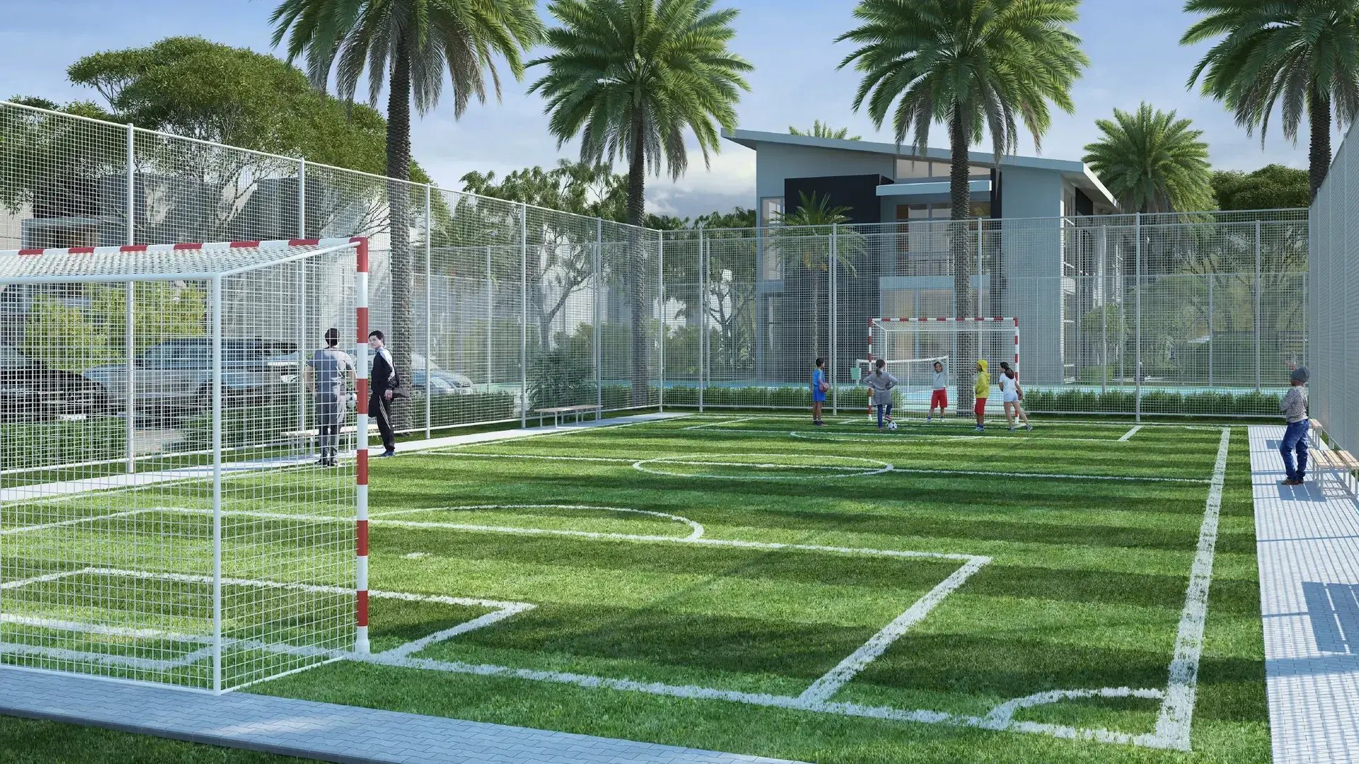 Render de cancha de fútbol 5 con césped sintético en Condominio Nasara, Santa Ana. Muestra el cerramiento perimetral de malla, marcos de fútbol, niños jugando y la Casa Club al fondo rodeada de palmeras.