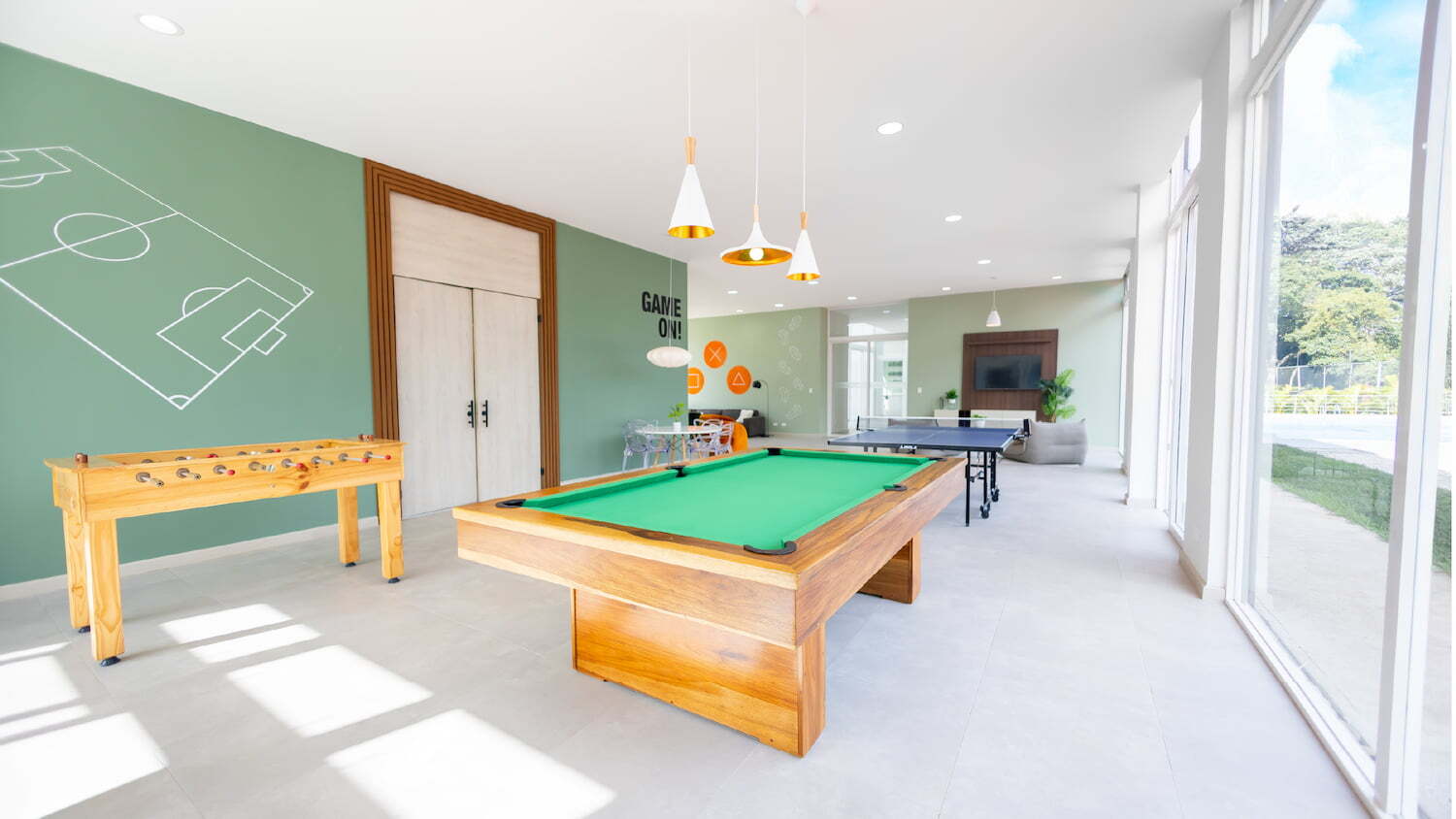 Sala de juegos comunitaria en Condominio Nasara con mesa de billar, futbolito, mesa de ping pong y un diseño moderno con iluminación natural.