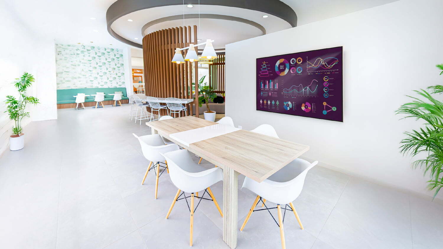 Sala de reuniones y espacio de coworking en las amenidades de Condominio Nasara con mesa de madera, sillas blancas y pantalla digital con gráficos en la pared.