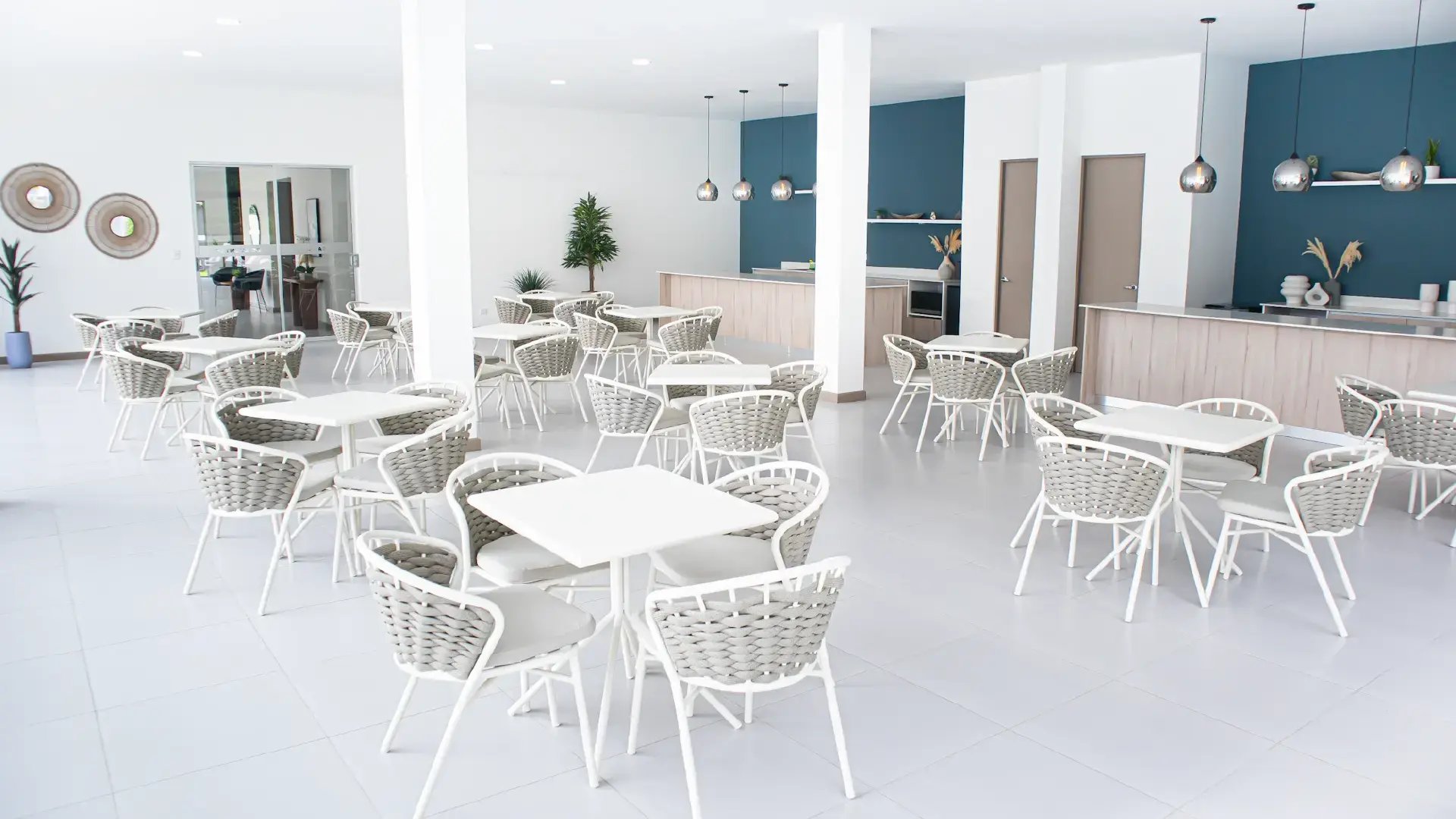Amplio salón multiuso en la Casa Club de Condominio Blue, Cariari. Muestra múltiples juegos de mesas y sillas de diseño contemporáneo, barras de servicio tipo buffet y una iluminación moderna en un espacio abierto y elegante.