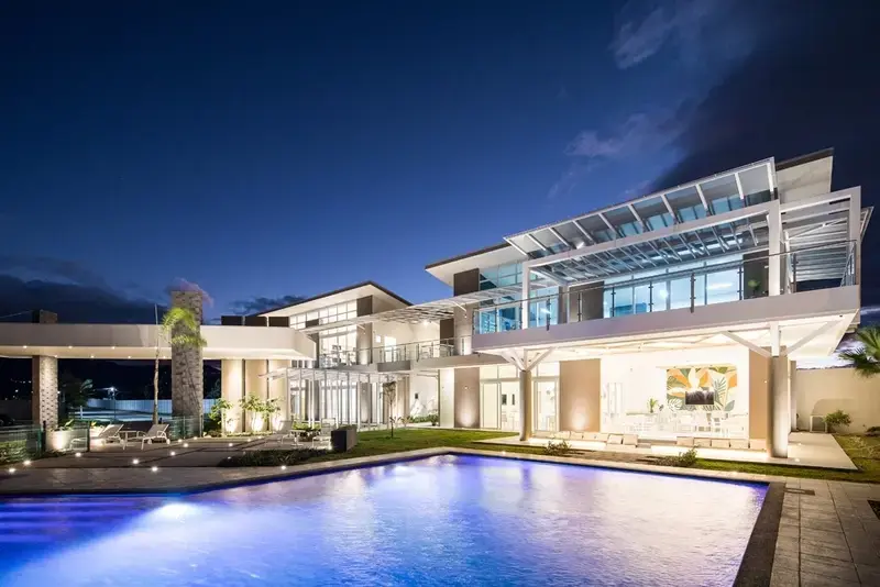 Casa moderna de lujo con piscina iluminada y áreas exteriores en la noche